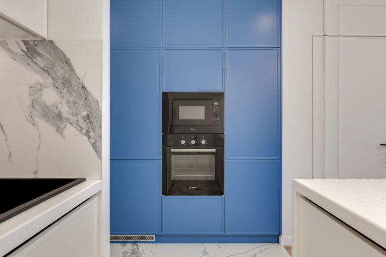 Moderne keuken met blauwe kastjes en een ingebouwde combimagnetron boven de oven